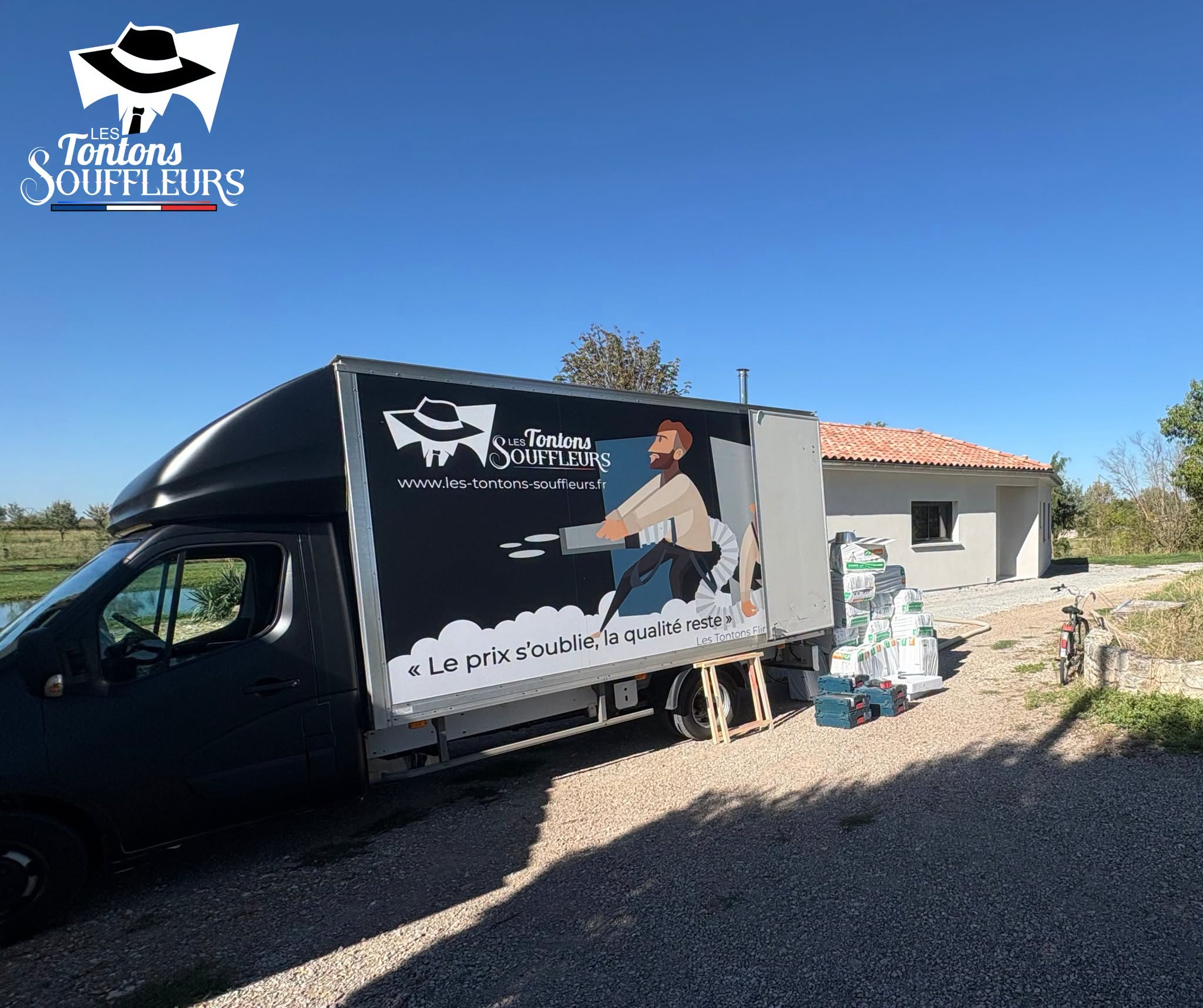 Camion des Tontons Souffleurs et sacs de ouate de cellulose devant une maison neuve
